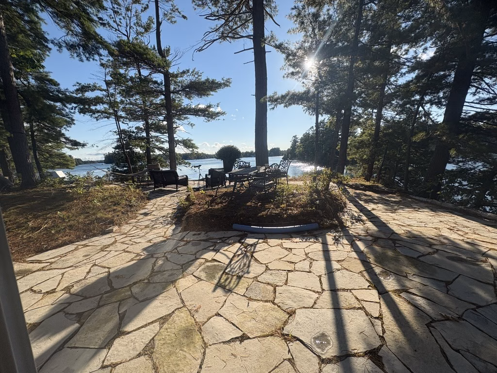 The stone patio and river view beneath tall island pines